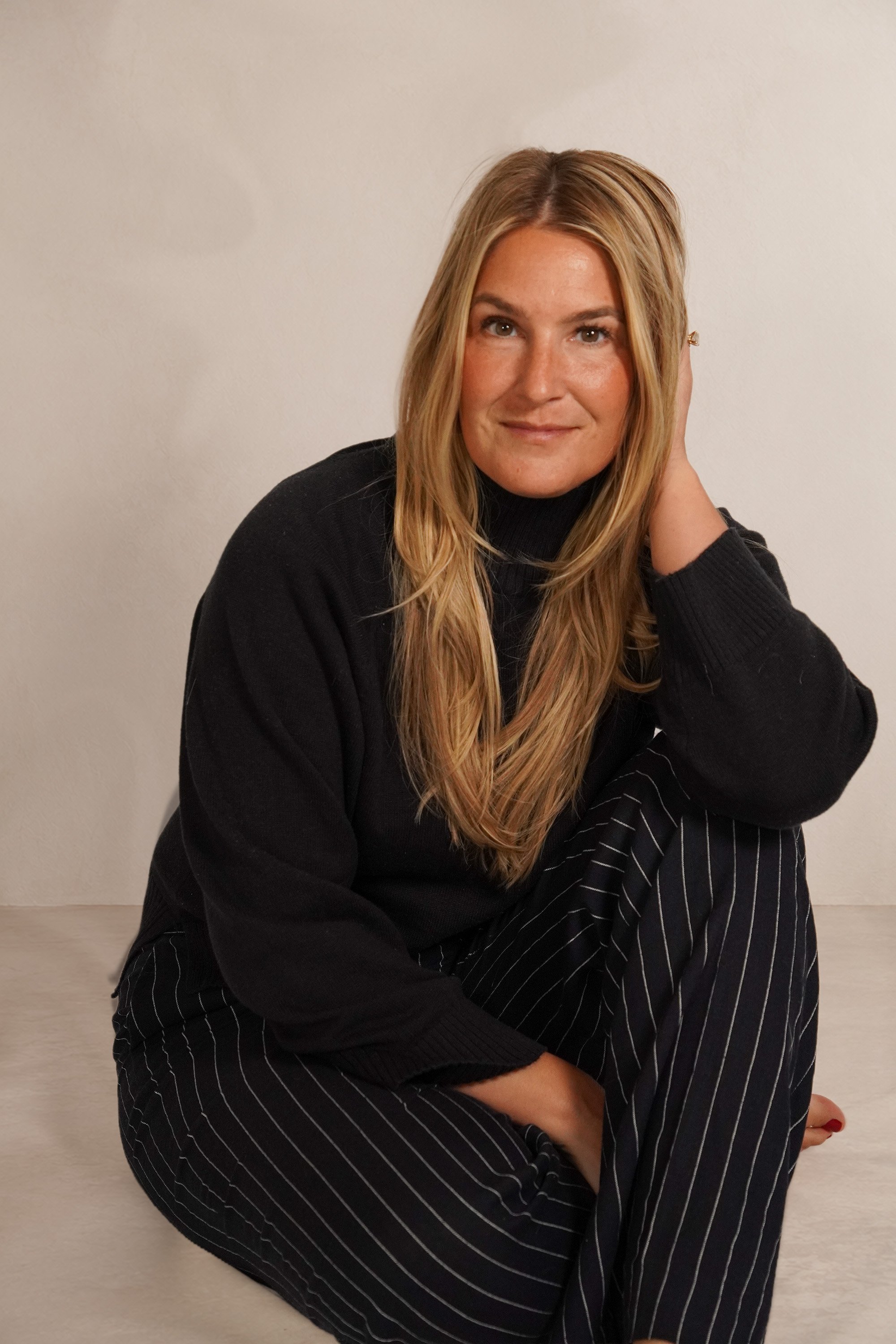 Bonnie seated in a black sweater with her hand beside her hair